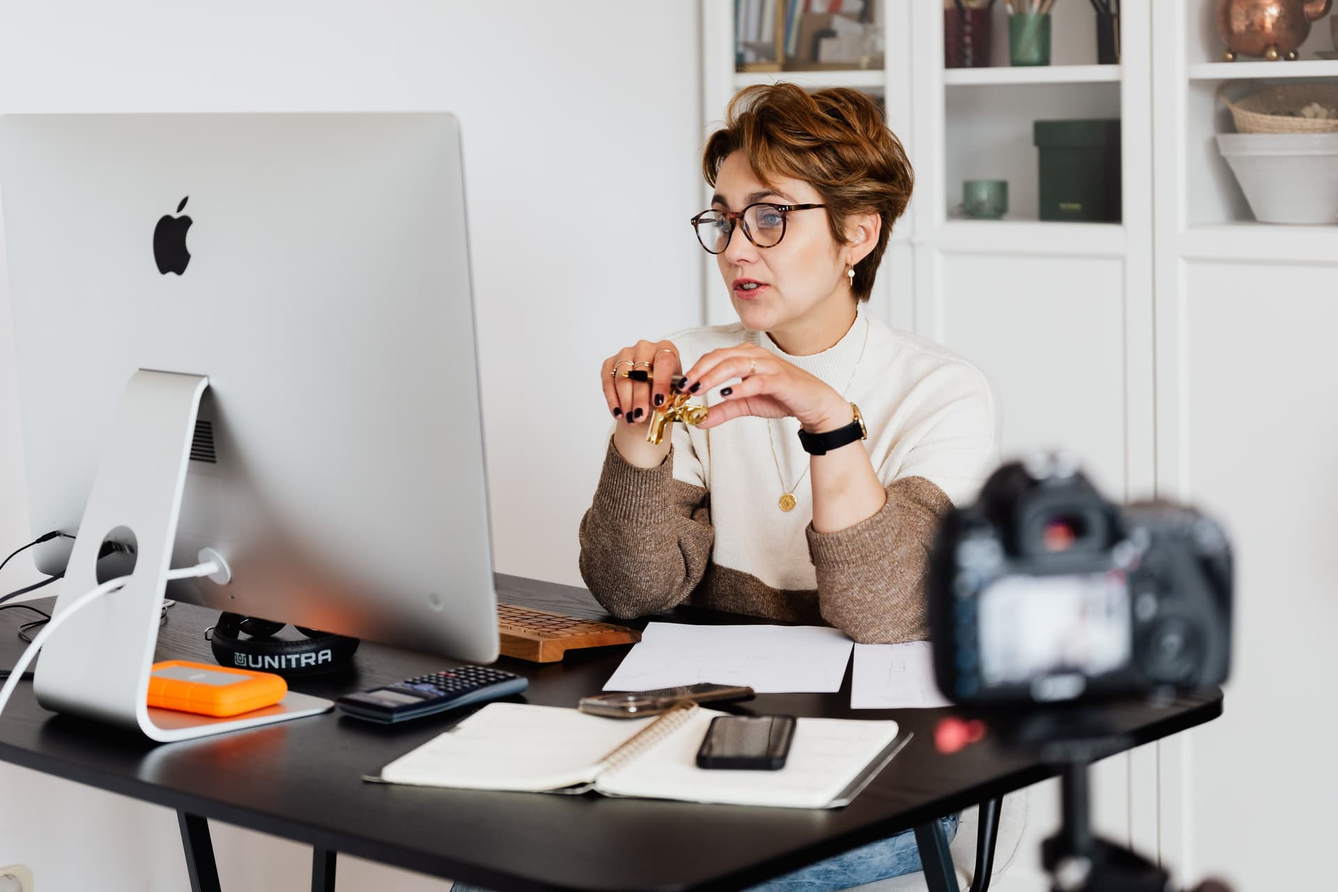 A woman is sitting behind a computer, leading a webinar.